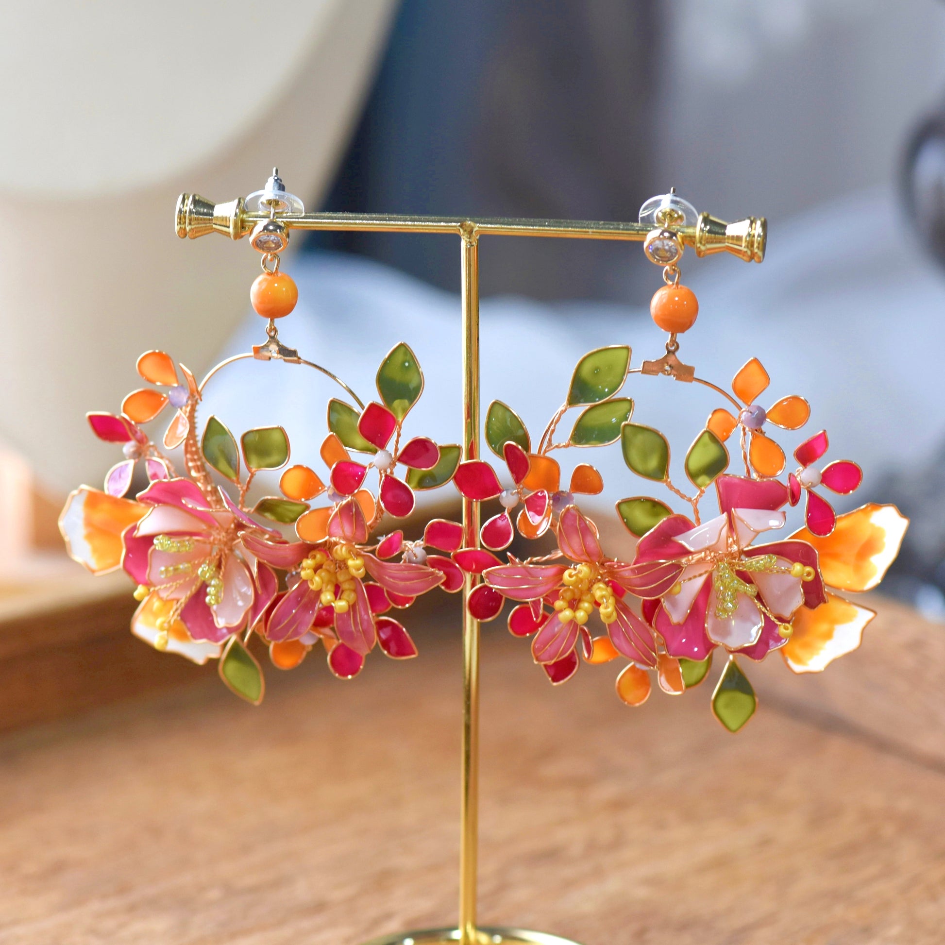 Close-up of Samara resin floral earrings vibrant pink orange petals yellow bead stamens golden copper wirework