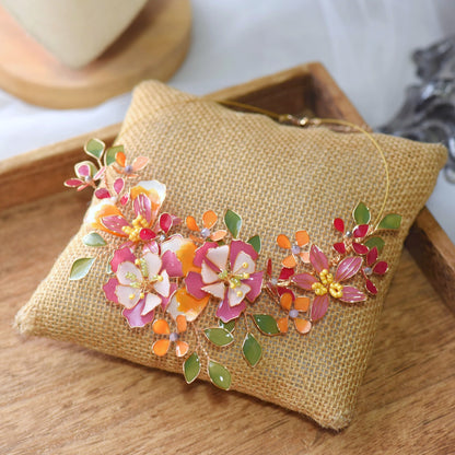 Samara handcrafted resin floral necklace vibrant pink coral orange green gold flat lay burlap cushion