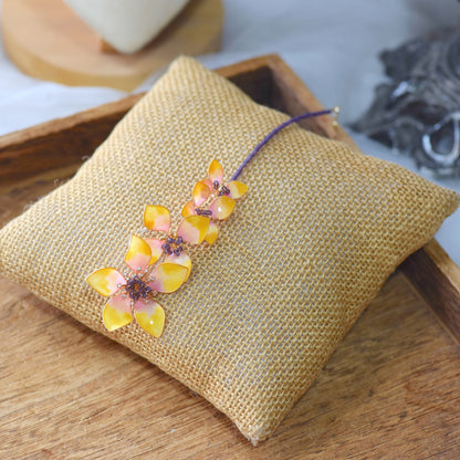 Seraphina handcrafted resin floral maang tika yellow peach gold violet bead accents flat lay burlap cushion
