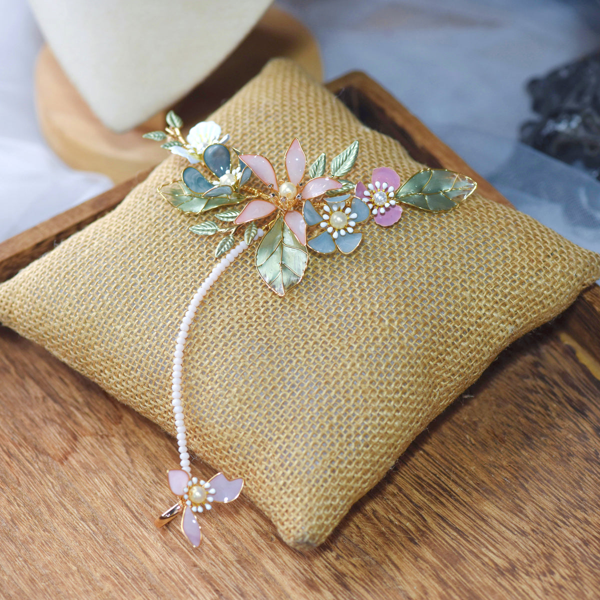 Shaylah pastel resin floral hand harness in green, pink and lavender laid on a jute cushion
