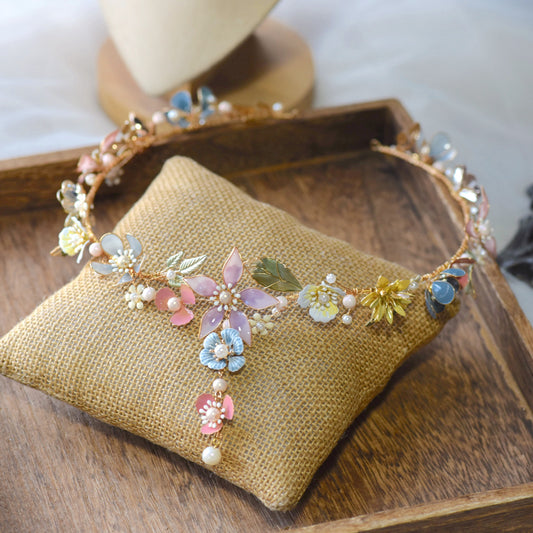 Shaylah pastel resin floral head harness in green, pink and lavender laid on a jute cushion

