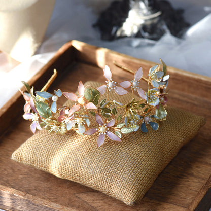Shaylah pastel resin floral crown headband in green, pink and lavender laid on a jute cushion
