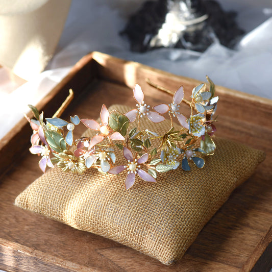 Shaylah pastel resin floral crown headband in green, pink and lavender laid on a jute cushion
