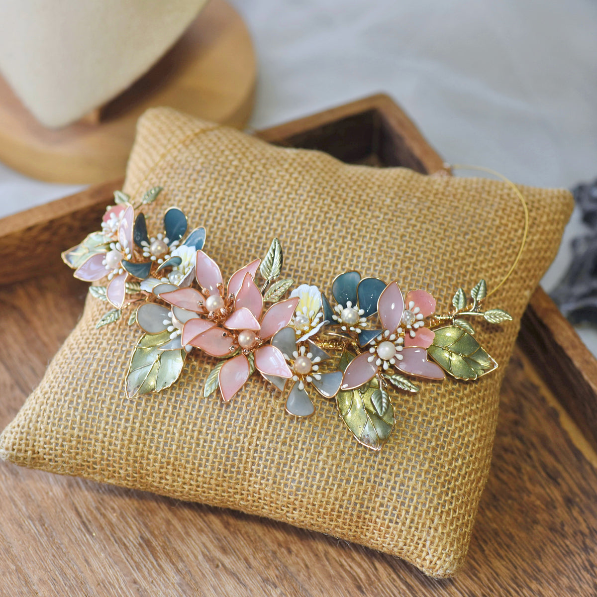 Shaylah pastel resin floral necklace in green, pink and lavender laid on a jute cushion
