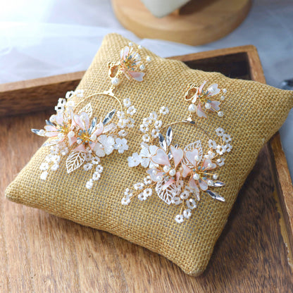 Sophia white and blush resin floral earrings laid on a jute cushion showing pearl and leaf detail
