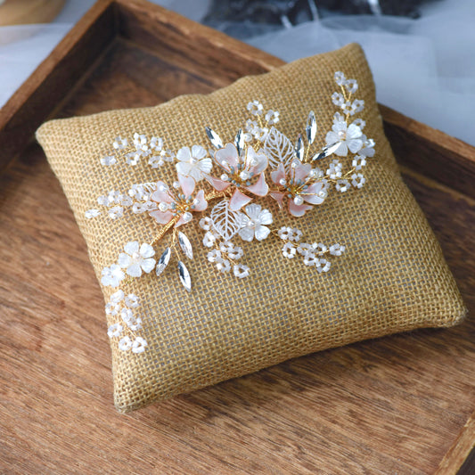 Sophia white resin floral bridal hair vine with imitation pearls laid on a jute cushion
