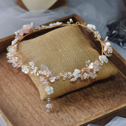 Sophia white resin floral head harness with imitation pearls laid on a jute cushion
