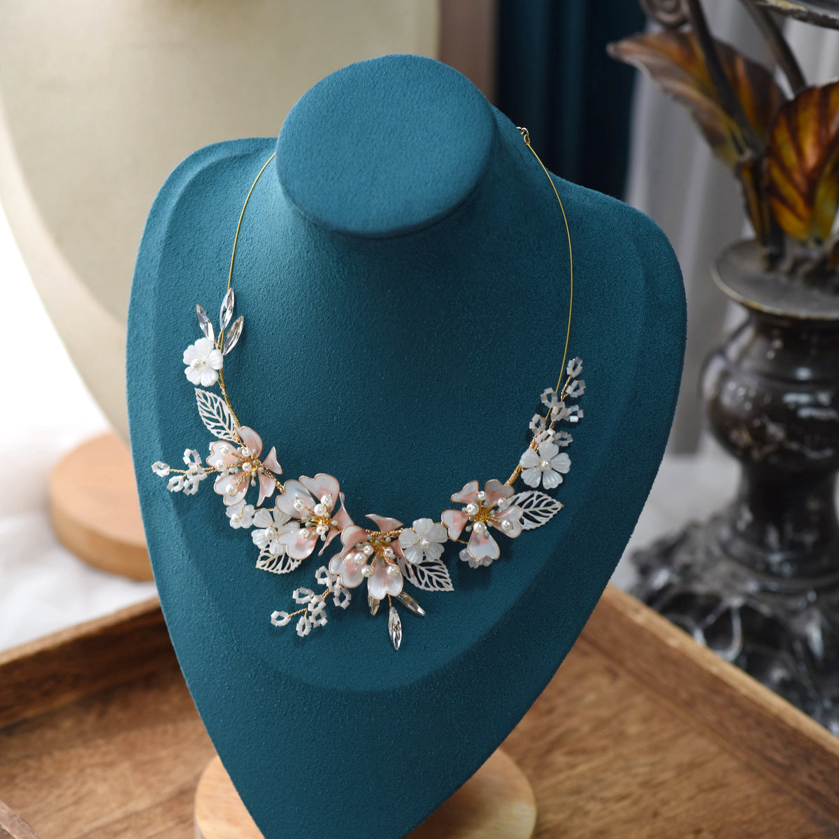Sophia white and pearl resin floral statement necklace displayed on a stand showing the garland design
