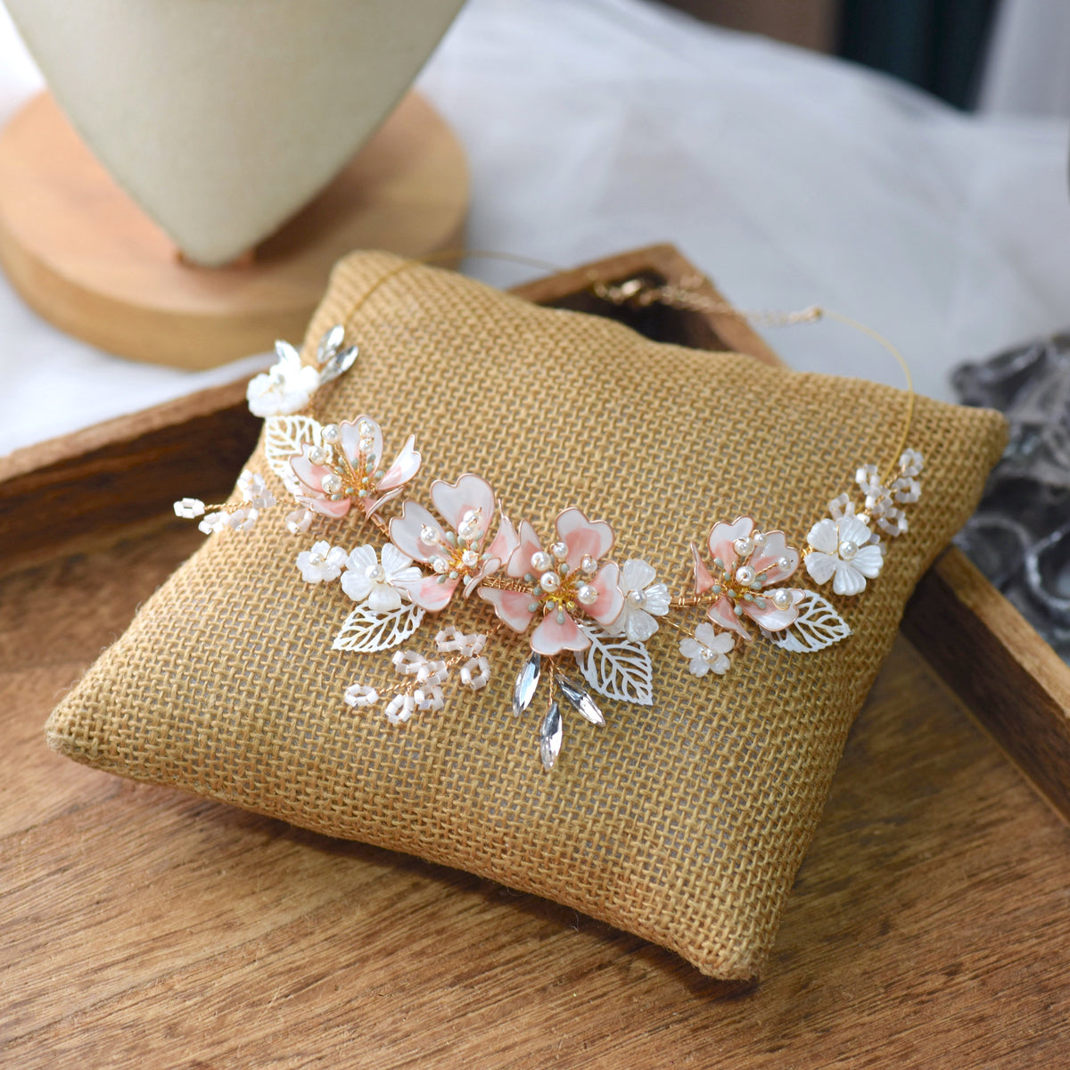 Sophia white resin floral necklace with imitation pearls laid on a jute cushion
