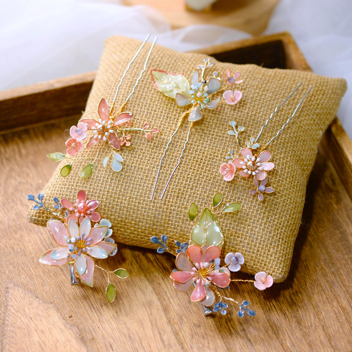 Trina coral and green floral hair clips laid on a jute cushion showing bloom and leaf detail
