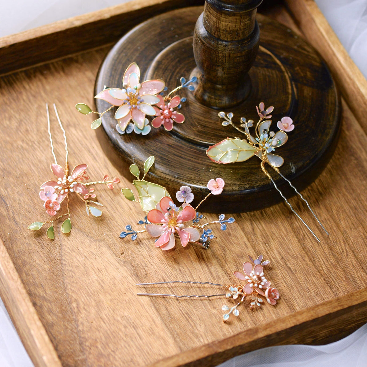 Trina set of five coral and green resin floral hair pins arranged on a wooden tray
