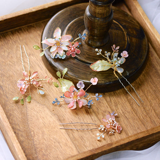 Trina set of five coral and green resin floral hair pins arranged on a wooden tray
