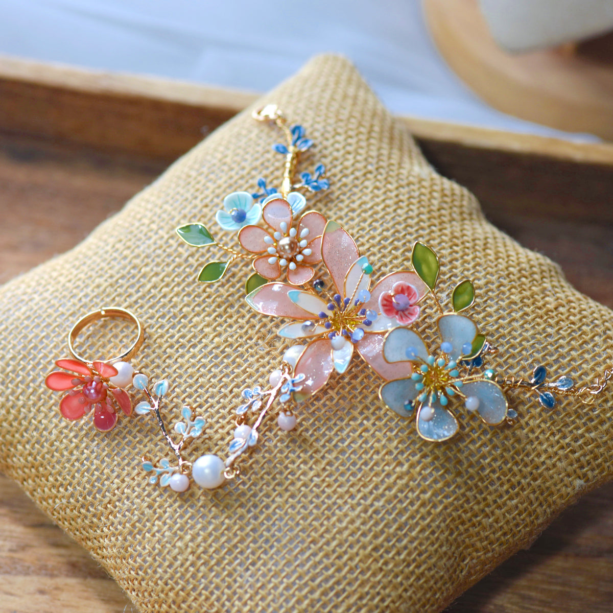 Trina coral and green resin floral hand harness with pearl beads laid on a jute cushion
