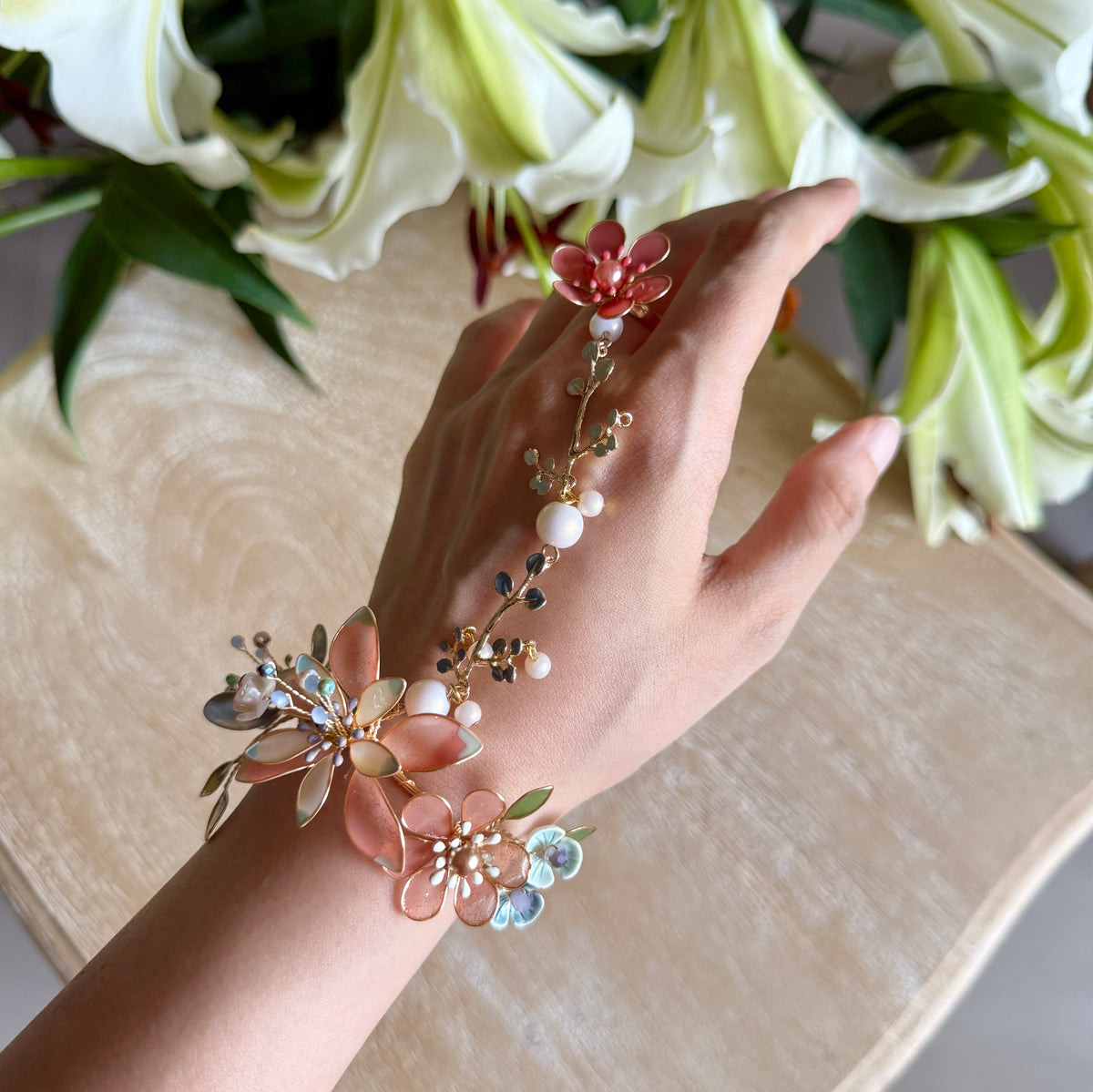 Close view of the Trina hand harness worn on the hand showing the golden vine, pearl beads and coral blooms
