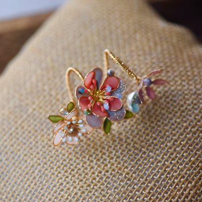 Trina coral resin floral statement ring with pearl centre and green leaves on a jute cushion

