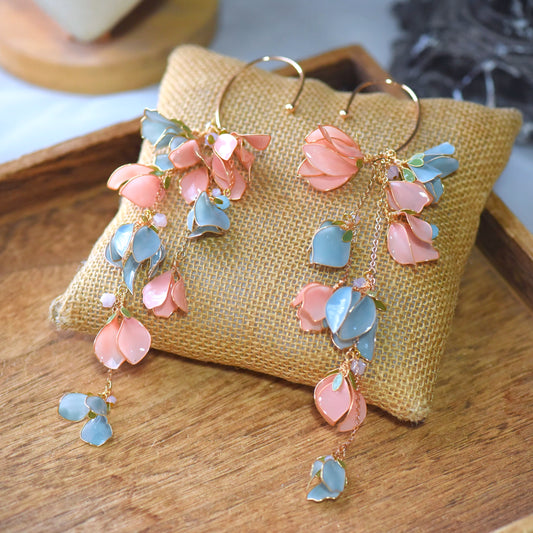 Verona peach and sky blue resin floral cascading ear cuffs on a jute cushion
