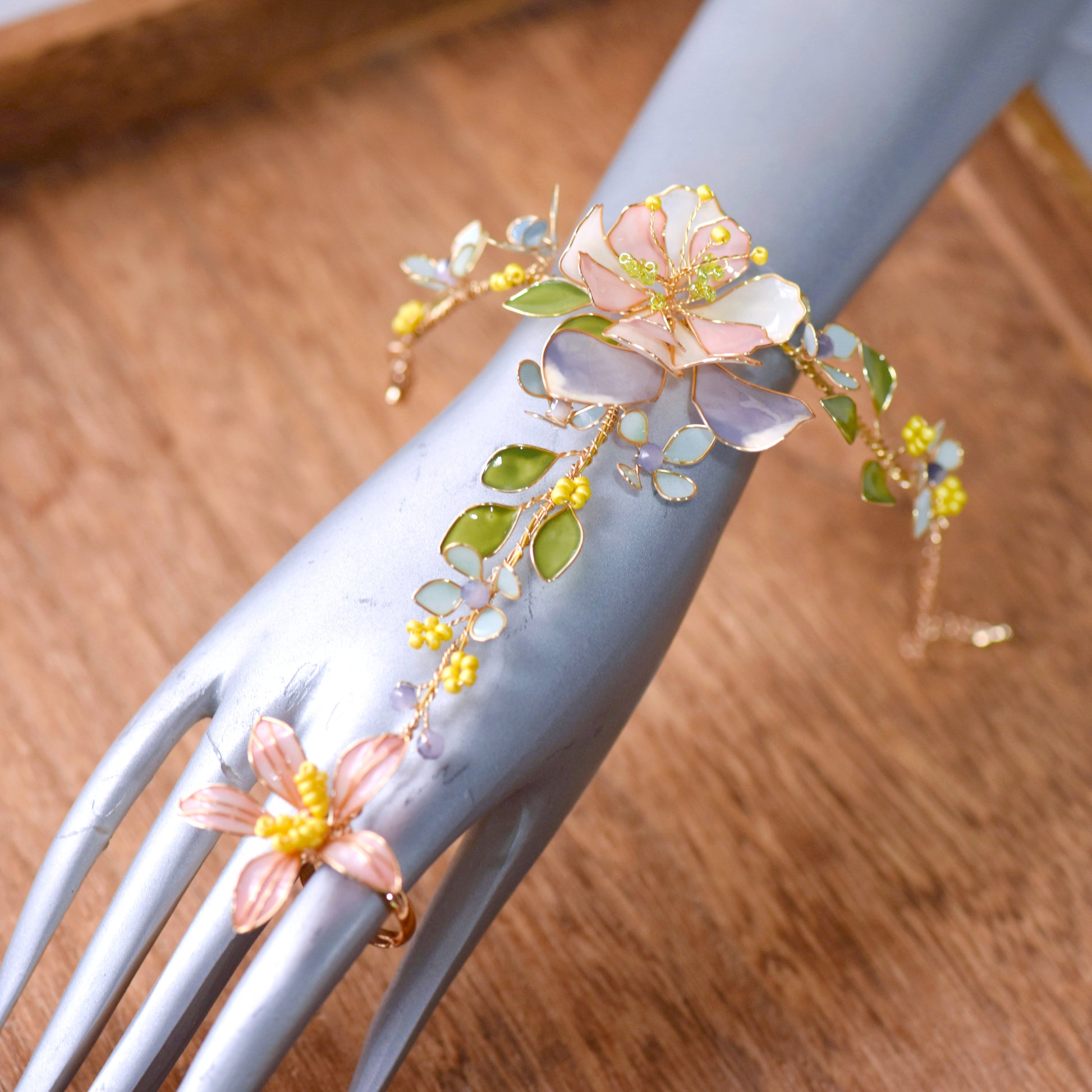 Close-up of Zahara haath phool handcrafted resin florals golden copper wirework on hand white background