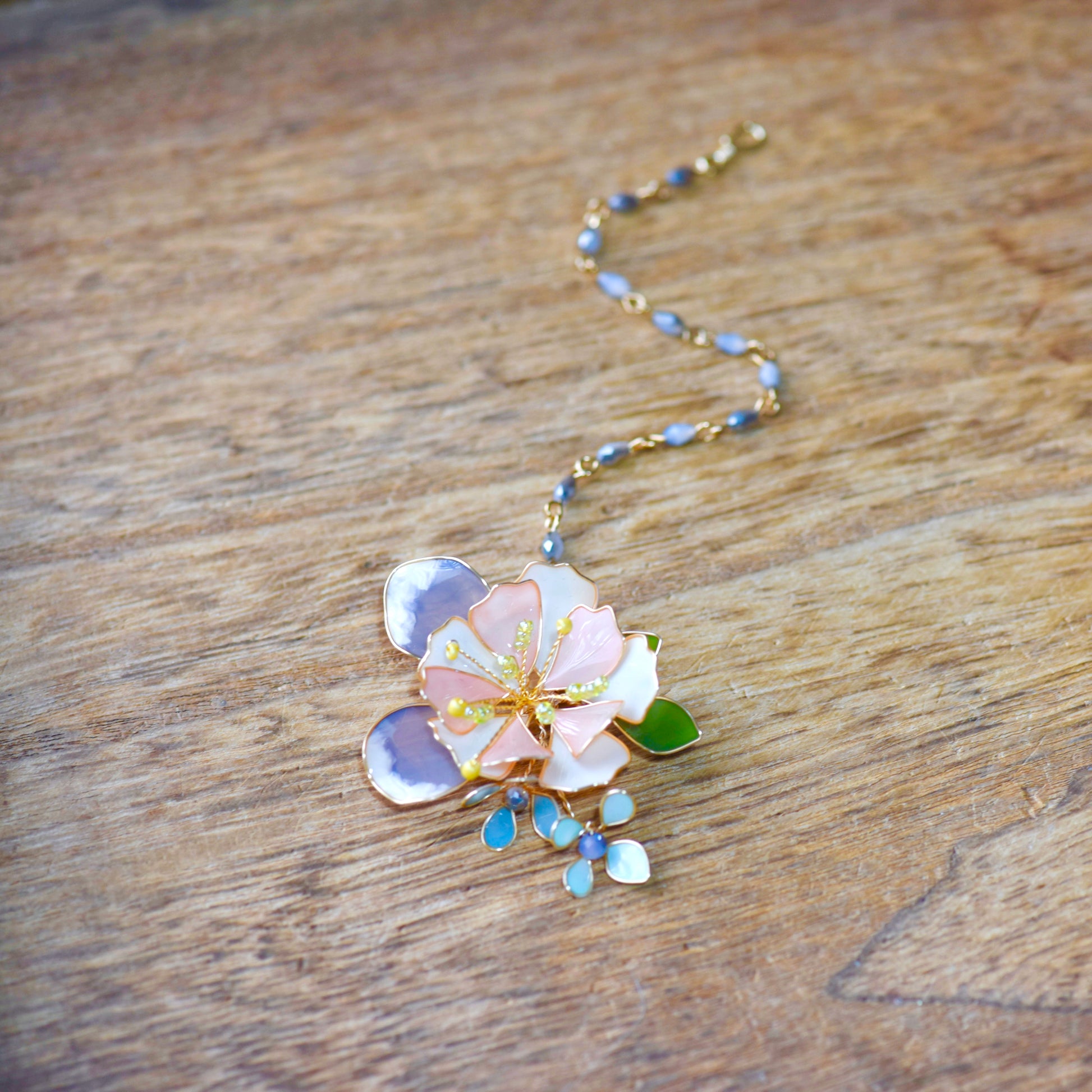 Close-up of Zahara maang tikka handcrafted resin petals golden copper wirework pale blue accents yellow stamens