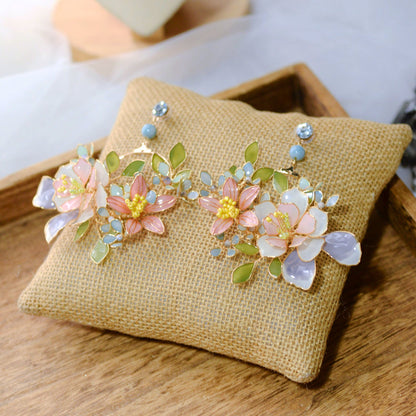 Close-up of Zahara resin floral earrings with yellow bead stamens pale blue accent and golden copper wirework
